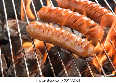 Grilling sausages over flames on the grill.