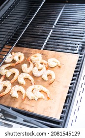 Grilling shrimp on a grill mat over an outdoor gas grill.