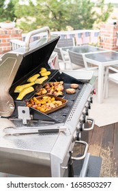 Grilling Small Potatoes With Slices Of Garlic On An Outdoor Gas Grill.