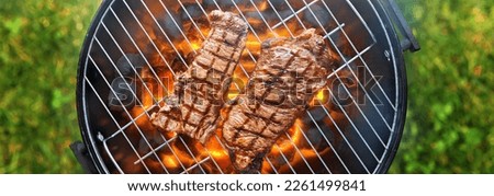 grilling steaks on charcoal bbq grill outdoors in yard shot from top view