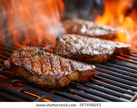 grilling steaks on flaming grill and shot with selective focus