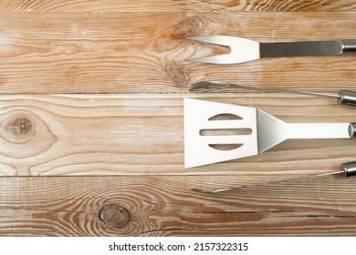 Grilling tools set on wood background. BBQ metal equipment, steel barbecue fork, tong, spatula on wood table background with copy space - Shutterstock ID 2157322315