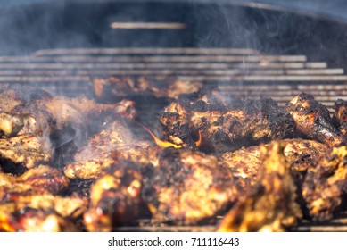 Grilling traditional Jamaican spicy jerk chicken with over wood fire.
