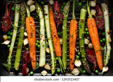 Grilling vegetables, raw vegetables prepared for grilling with the addition of olive oil, herbs and spices located on the grill plate, top view. Healthy nutrition concept, vegan meal