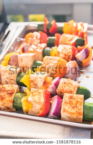 Grilling vegetarian tofu kebab with vegetables marinated in spicy sauce.