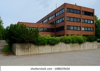 Grim Office Brick Building And Concrete Flowerbed With Plants