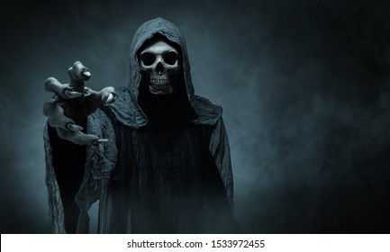 Grim reaper reaching towards the camera over dark background with copy space - Shutterstock ID 1533972455
