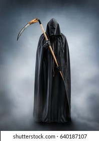 Grim Reaper standing in the fog at night. Photo of personification of death wielding a large scythe in silhouette.