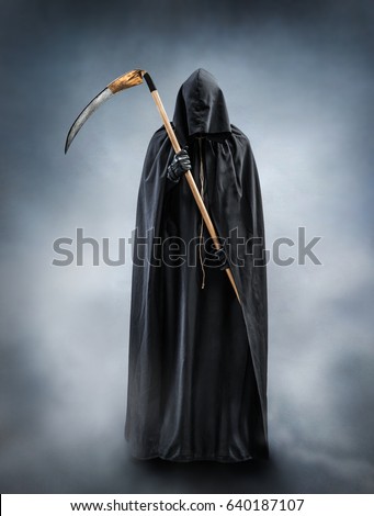 Grim Reaper standing in the fog at night. Photo of personification of death wielding a large scythe in silhouette.