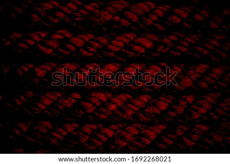 Grim rope wound in rows, illuminated in red. Ominous backdrop.