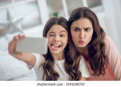 Grimacing funny daughter with mom taking selfie