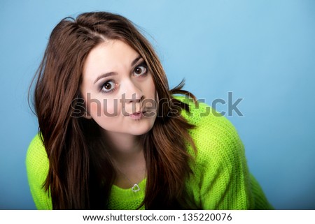 Grimacing young woman making silly face on blue background
