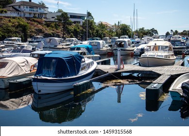 Grimstad, Norway - July 8th 2019: small white boats, with motors, at the pier, in the summer. Blue water. 