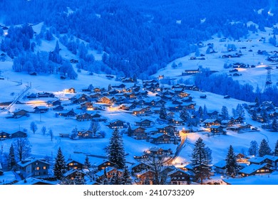 Grindelwald villages with wooden chalets covered with snow in cold winter season at the blue hours in Swiss Alps - Powered by Shutterstock