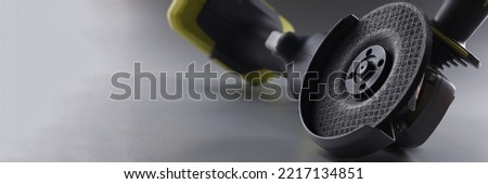 Grinder for metal works, electrical saw placed on grey background
