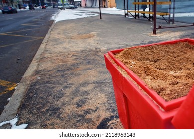 Grit bin, sand box with sand for improve traction on snowy and icy sidewalk at bus stop, road maintenance in winter season. Plastic grit container, spread sand to prevent slipping. SELECTIVE FOCUS - Shutterstock ID 2118963143
