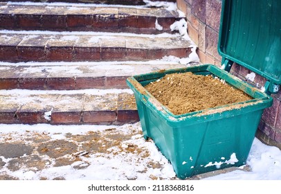 Grit bin, sand for improve traction on snowy and icy steps during winter season. Green plastic grit container, road maintenance in winter. Container with gritting material, prevention slippery surface - Shutterstock ID 2118368816