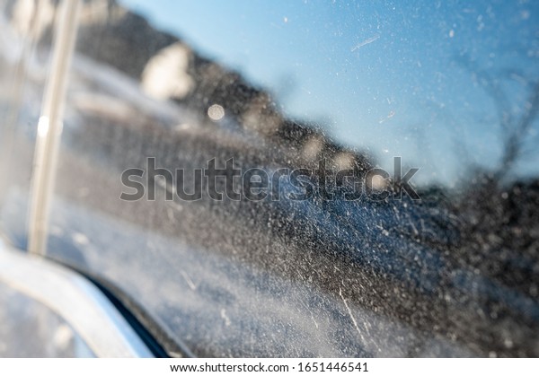 Grit and dust covered window of a vehicle with\
reflection of residential\
area