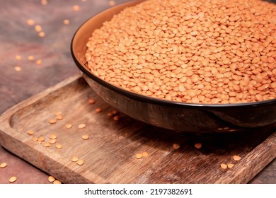 Grits Of Red Uncooked Raw Lentils Close-up In A Large Bowl On A Brown Background