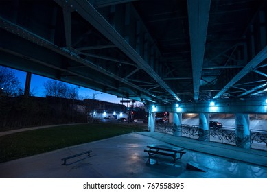 Gritty dark Chicago highway bridge underpass and city street with traffic and a bench at night. - Powered by Shutterstock