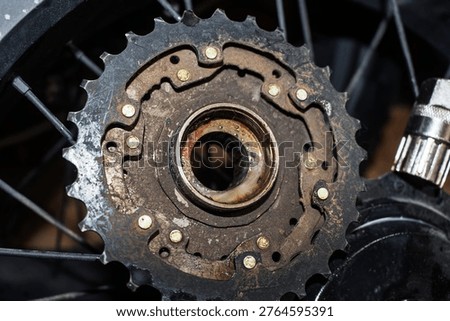 Gritty e-bike freewheel being removed from geared motor wheel with a tool. Dirty, worn bicycle drivetrain component maintenance in progress