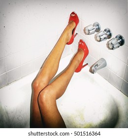 Gritty snapshot style image of slender woman's legs in high heel shoes passed out drunk in a motel bathtub after a party