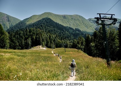 a groa group of tourists walks along a mountain path to the ascent to the mountainsup of tourists walks along a mountain path to the ascent to the mountains