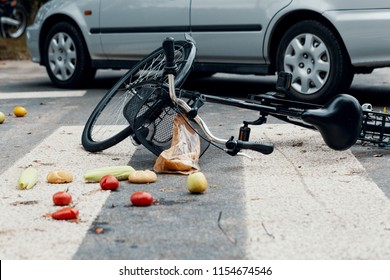 Groceries and broken bike on pedestrian crossing after collision with a car
