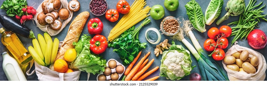 Groceries shopping. Flat lay of fruits, vegetables, greens, bread and oil in eco friendly bags, top view. Healthy eating and sustainability concept