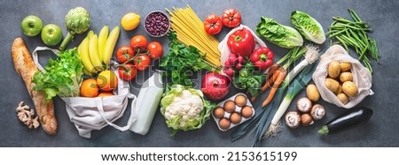 Groceries shopping. Flat lay of fruits, vegetables, greens, bread and oil in eco friendly bags, top view. Healthy eating and sustainability concept