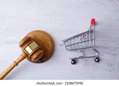 grocery cart and judge gavel on white brick wall background, consumer protection concept - Shutterstock ID 2108675990