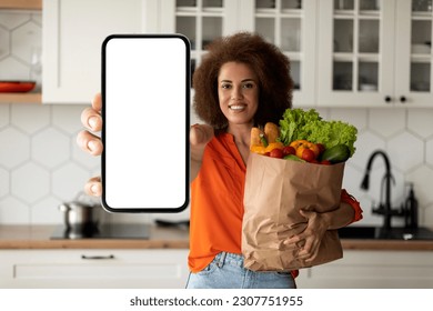 Grocery Delivery App. Smiling Black Woman Showing Blank Smartphone And Paper Bag With Groceries, Happy African Female Holding Empty Cellphone In Hand, Advertising Application Or Website, Mockup - Powered by Shutterstock