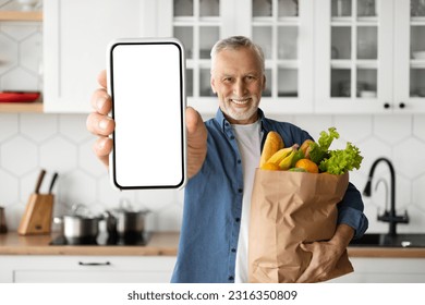 Grocery Delivery App. Smiling Senior Man Showing Blank Smartphone And Holding Paper Bag With Groceries, Happy Elderly Male Demonstrating Empty Cellphone, Advertising Application Or Website, Mockup - Powered by Shutterstock