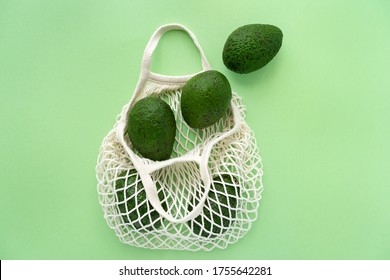 Grocery Eco Mesh Cotton Bag With Avocado.Vegetarianism. Eco Friendly Shopping And Healthy Lifestyle Concept. Top View. Minimalism Style. Flat Lay Avocados On Green Background. Zero Waste, Plastic Free