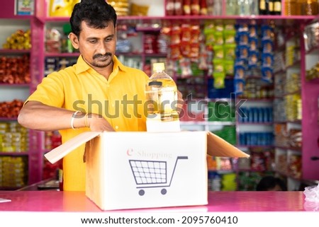 Grocery or kirana store shopkeeper packing groceries on e-commerce shopping box at retail store - concept of Online business, home delivery for online booking and new business opportunities