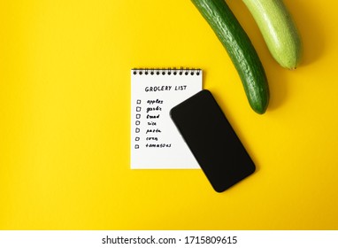 Grocery List Paper Notepad And Smartphone, Zucchini And Cucumber On Yellow Background With Copy Space, Above. Concept Online E-commerce, Horizontal