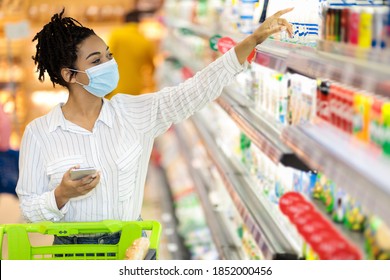 Grocery Shopping. African American Woman Wearing Protective Face Mask In Supermarket, Buying Food Products In Groceries Store Indoor. Female Buyer With Shop Cart In Hypermarket