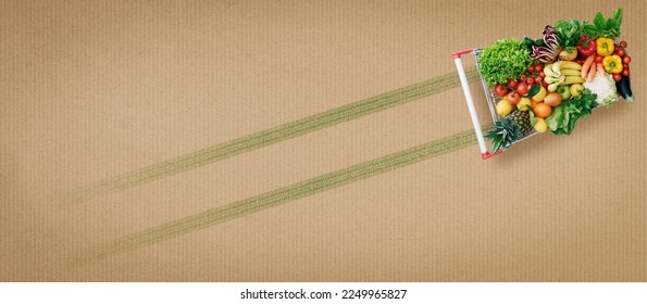 Grocery shopping banner: shopping cart full of vegetables and fruits leaving a green track on the background: organic food and sustainability concept - Powered by Shutterstock