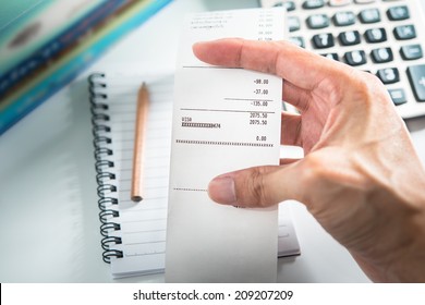 Grocery shopping list in hand with calculator and pencil - money account management concept