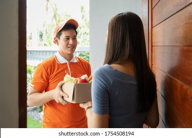 Grocery Store Delivery Man Wearing Orange Polo-shirt Delivering Food To A Woman At Home