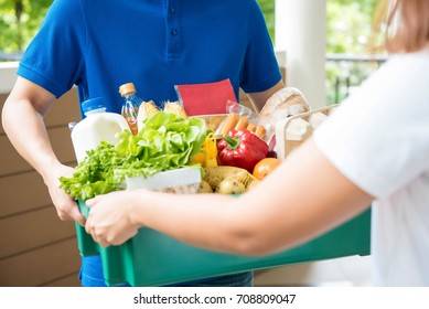 A Grocery Store Delivery Man Wearing A Blue Polo-shirt Delivering Food To A Woman At Home