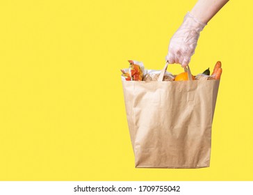 A Grocery Store Delivery Service Worker Gives A Gloved Paper Bag To Protect Against COVID-19 Coronavirus With Copy Space.