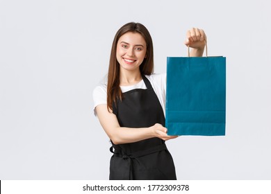 Grocery store employees, small business and coffee shops concept. Friendly helpful, smiling saleswoman handing over customer their bag with purchase, clerk or cashier processing order - Powered by Shutterstock