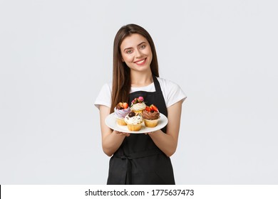 Grocery store employees, small business and coffee shops concept. Friendly smiling waitress bring desserts to cafe vistitor. Smiling cute barista showing delicious cupcakes on menu