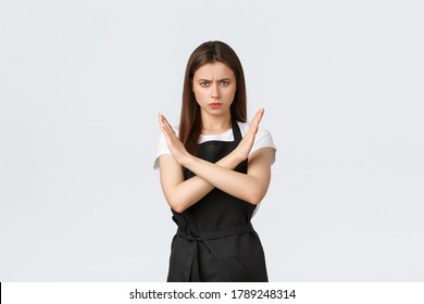 Grocery Store Employees, Small Business And Coffee Shops Concept. Serious Displeased Frowning Barista In Black Apron Show Cross Stop Gesture, Forbid Something, Express Disapproval