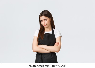 Grocery store employees, small business and coffee shops concept. Annoyed and bothered female barista smirk unsatisfied and looking away irritated, cross arms chest, standing white background