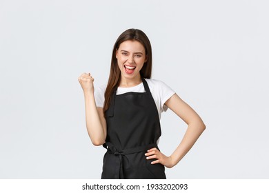 Grocery Store Employees, Small Business And Coffee Shops Concept. Happy Female Barista In Black Apron Fist Pump In Rejoice, Celebrating Great Achievement Or Success