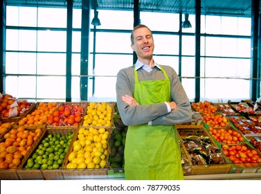 A Grocery Store Owner Standing In Front Of Vegetables And Fruit