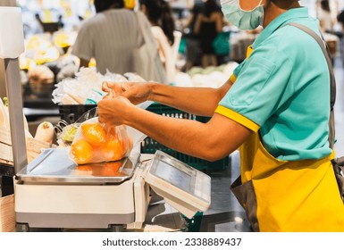 Grocery Store staff weighing oranges in plastic bag on digital scales. - Powered by Shutterstock