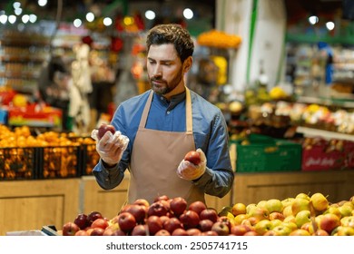 Grocery store worker organizing apples in produce section, emphasizing freshness and quality. Employee wearing apron and gloves focuses on sorting fruit in vibrant supermarket environment - Powered by Shutterstock